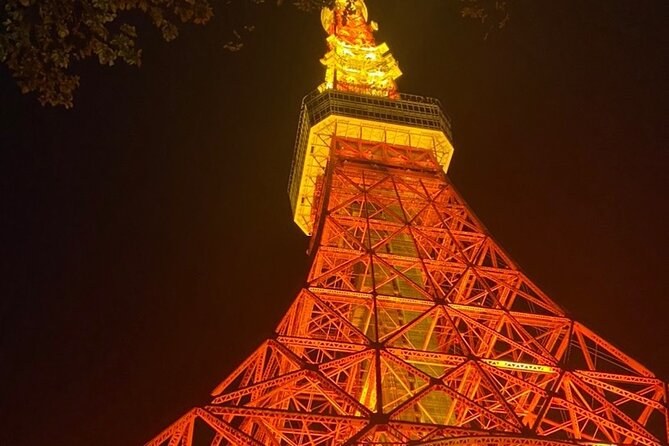 A red lattice tower lit orange from below against the night sky