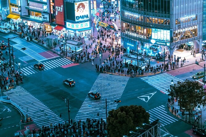 The scramble crossing from above after dark, crowds crossing in every direction